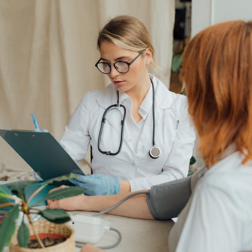 A female doctor checks a patient's blood pressure during a routine consultation in a clinic.